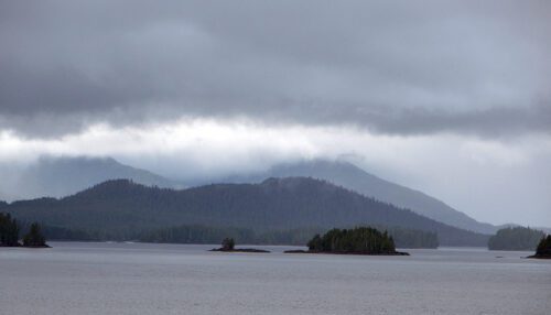 a gray sky full of clouds over a grey lake