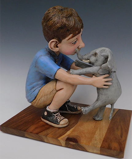 sculpture of boy holding small elephant